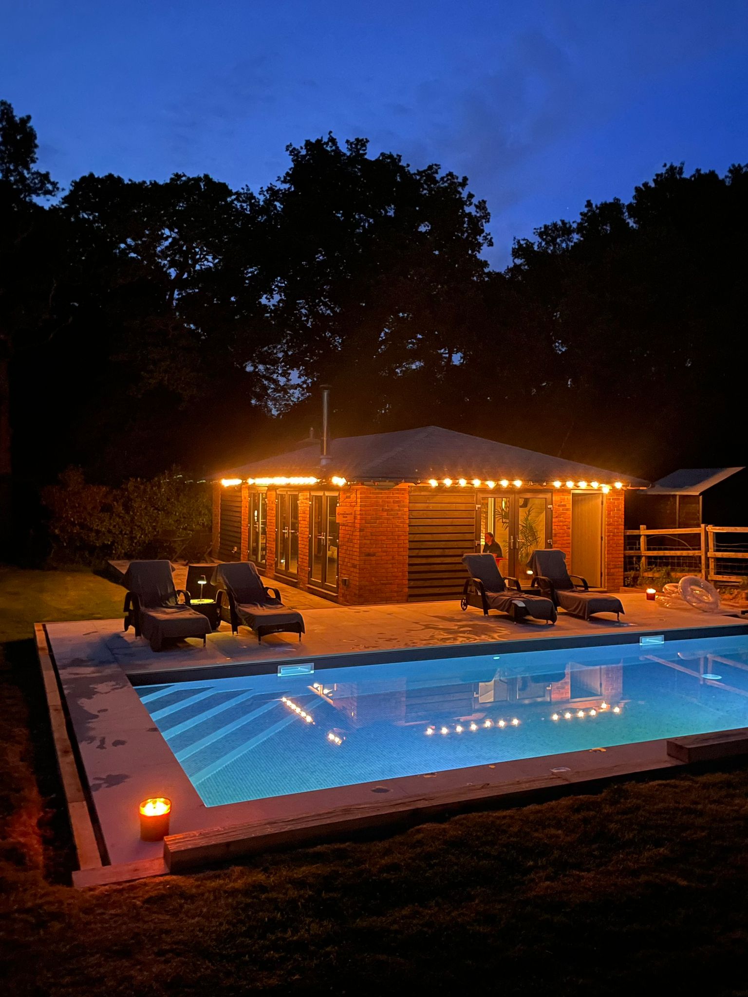 Illuminated swimming pool and pool house at night