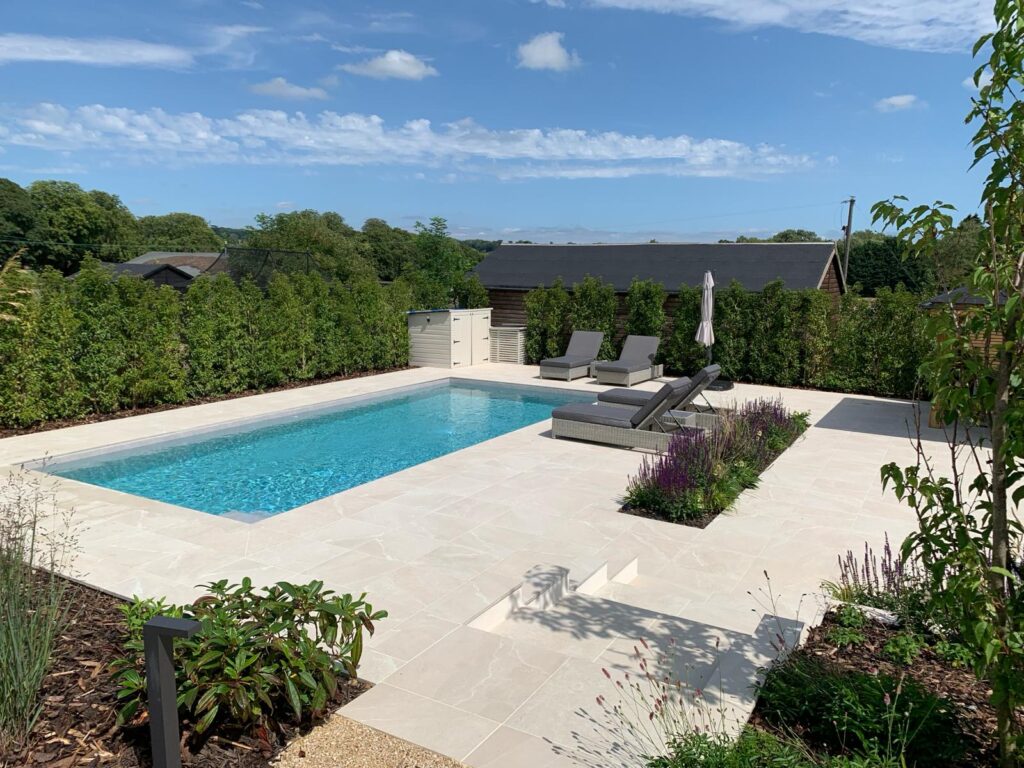 Modern outdoor swimming pool with tiled patio and sun loungers