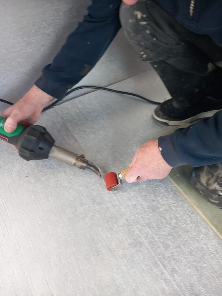 Worker sealing flooring joints with heat welding tool