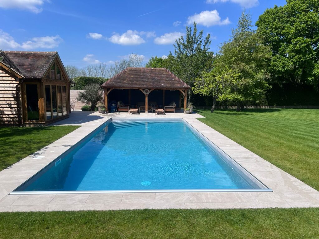 Luxury outdoor swimming pool with landscaped garden and pool house