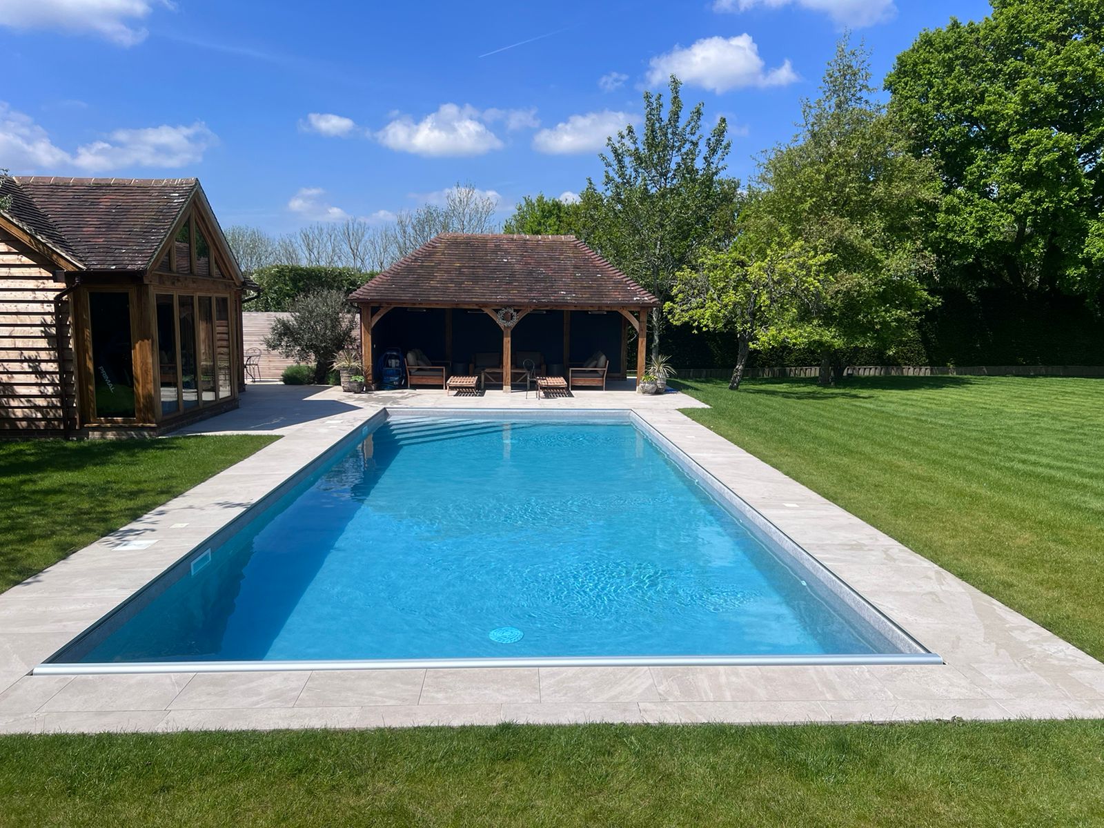 Luxury outdoor swimming pool with landscaped garden and pool house